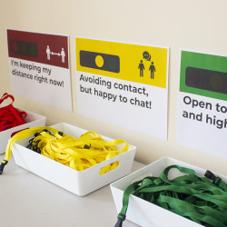 Traffic Light Lanyards for Social Distancing Green, yellow and red traffic light lanyards in separate baskets with posters above them